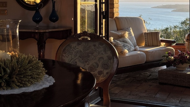 A cozy interior with a view of the sea, a round mirror, a dark wooden table, and a patterned chair. - Villa with panoramic pool • Passignano sul Trasimeno, Umbria (Passignano sul Trasimeno)
