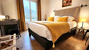 A hotel room with a bed, a desk, a chair, a lamp, and a poster on the wall. - Vilajoun (Joucas)