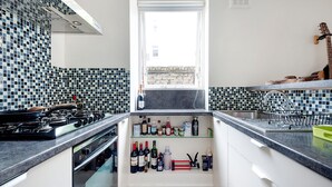 Eine Küche mit einem Gasherd, Weinflaschen und einem Fenster.