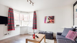 Ein modernes Wohnzimmer mit Holztisch, grauem Sofa und einem roten und schwarzen Streifenvorhang.