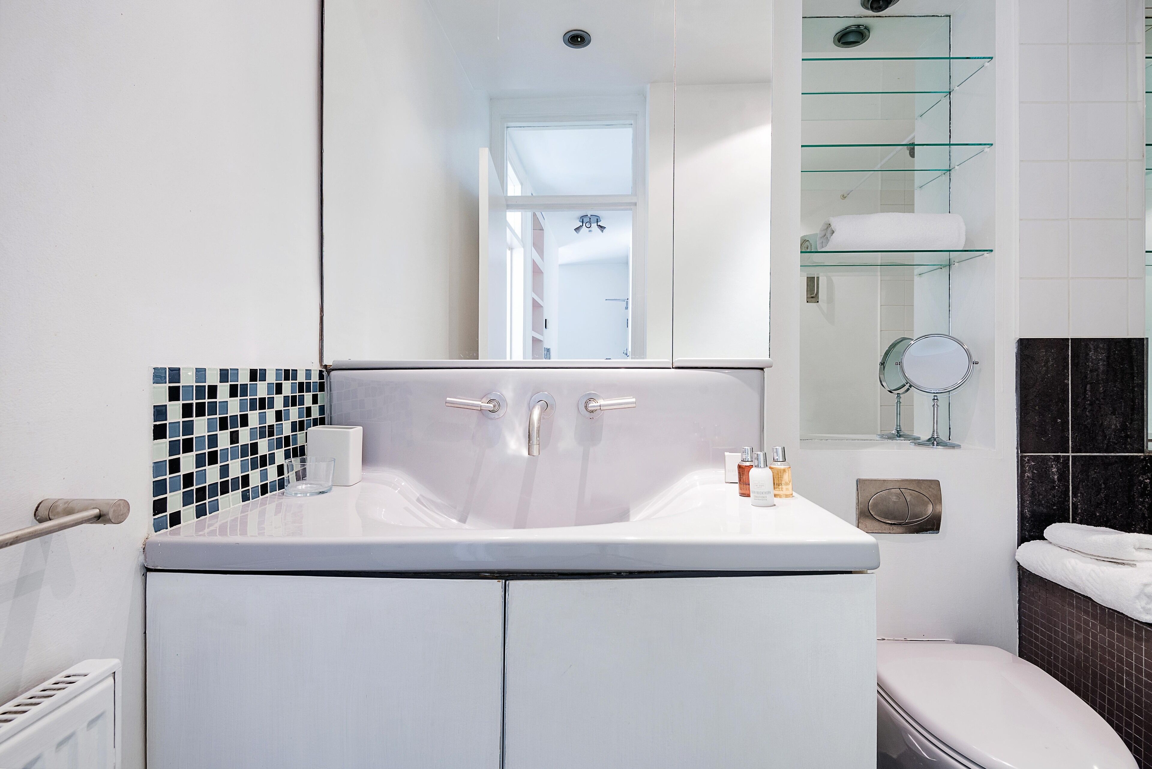 Une salle de bain moderne avec un lavabo blanc, une douche en verre et des toilettes.