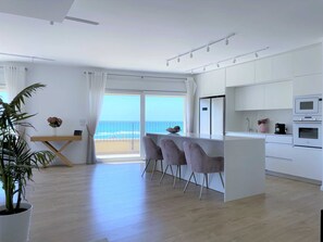 A modern kitchen with white cabinets, a dining area with a view of the ocean, and a potted plant. - Seafront penthouse - terrace, AC, lift & parking (Tel Aviv-Yafo)