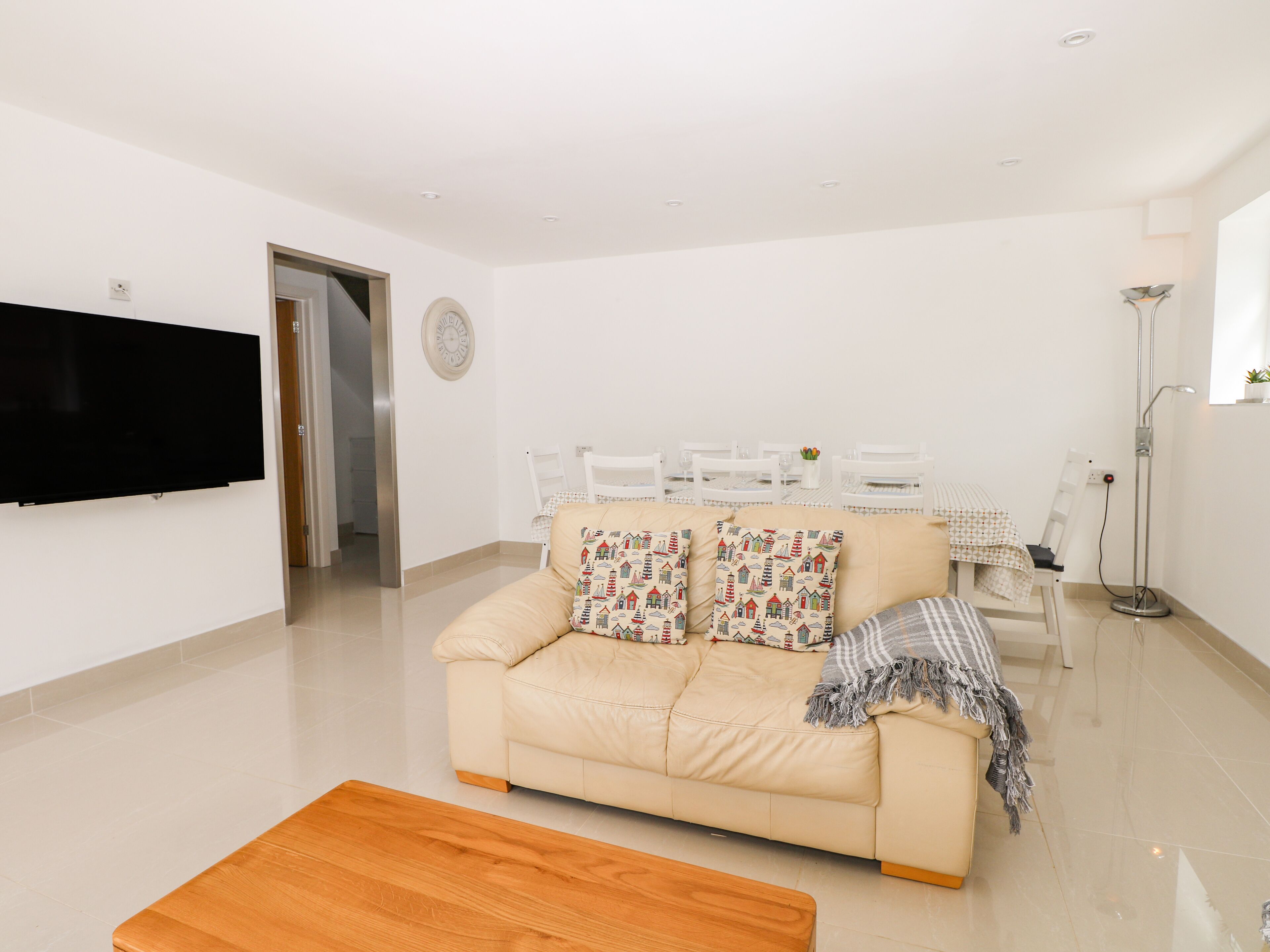 A modern living room with a sofa, a coffee table, a TV, and a dining area with chairs and a table.