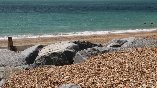 A rocky beach with pebbles and large boulders, leading to the sea. - Wheatlands (Hayling Island)