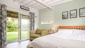 A bedroom with a bed, a chair, a window, and a door leading to a balcony. - Wheatlands (Hayling Island)