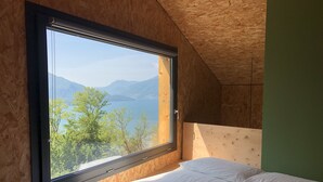 A bedroom with a large window, a bed, and a view of a lake and mountains. - COTTAGE Elena by KlabHouse-4pax w/AC & Lakeview  (Dolo)