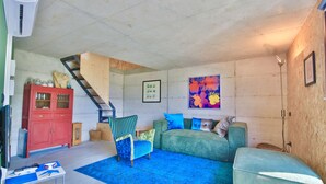 A living room with a staircase, a red cabinet, a green sofa, a blue armchair, and a blue rug. - COTTAGE Elena by KlabHouse-4pax w/AC & Lakeview  (Dolo)