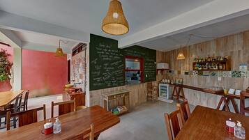 Un restaurante con mesas y sillas de madera, un menú en una pizarra y una zona de bar.