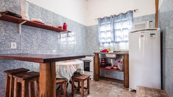 A kitchen with a wooden table, stools, a stove, a microwave, and a refrigerator.
