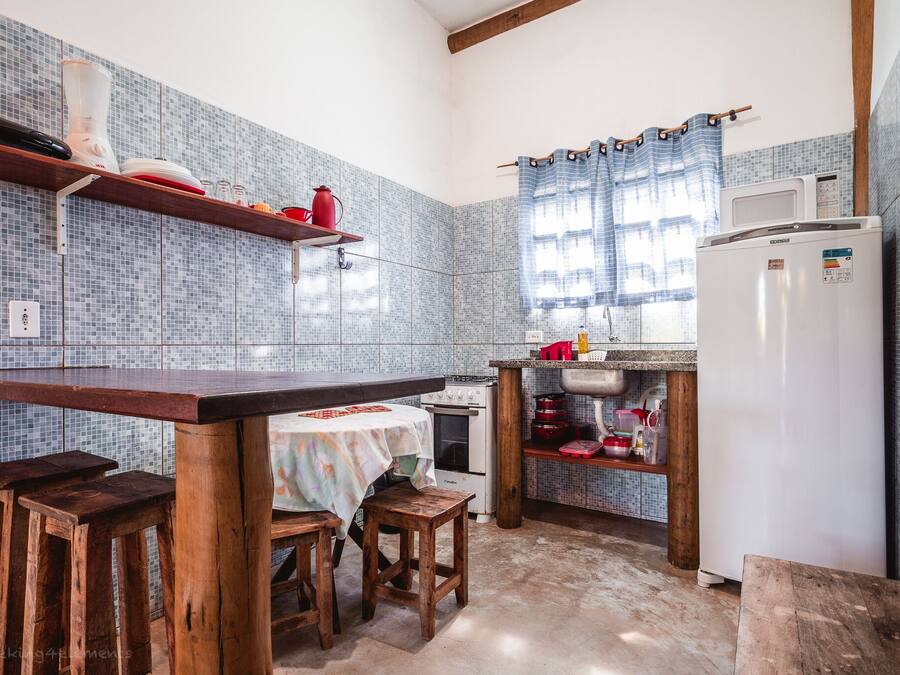 A kitchen with a wooden table, stools, a stove, a microwave, and a refrigerator.