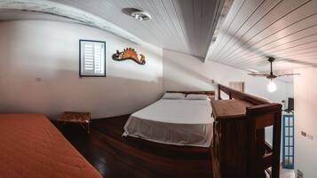 A room with a bed, a small stool, a wooden bench, and a ceiling fan.