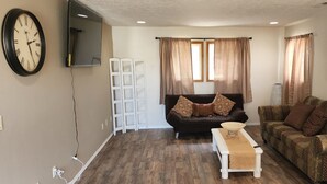 A living room with a brown sofa, a patterned couch, a white bench, and a wall-mounted clock. - A Wine Country  Home (Lafayette)