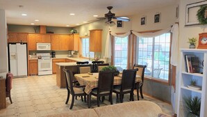 A kitchen with wooden cabinets, a white refrigerator, a stove, and a dining area with a table and chairs. - A Wine Country  Home (Lafayette)