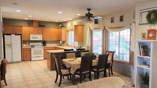 A kitchen with wooden cabinets, a microwave, a stove, and a dining area with a table and chairs. - A Wine Country  Home (Lafayette)