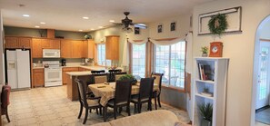 A kitchen with wooden cabinets, a microwave, a stove, and a dining area with a table and chairs. - A Wine Country  Home (Lafayette)