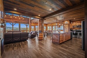 A spacious living area with a large sofa, a wooden bar, and a kitchen with modern appliances.