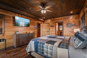 Ein Schlafzimmer einer Holzhütte mit Bett, Kommode und Deckenventilator.