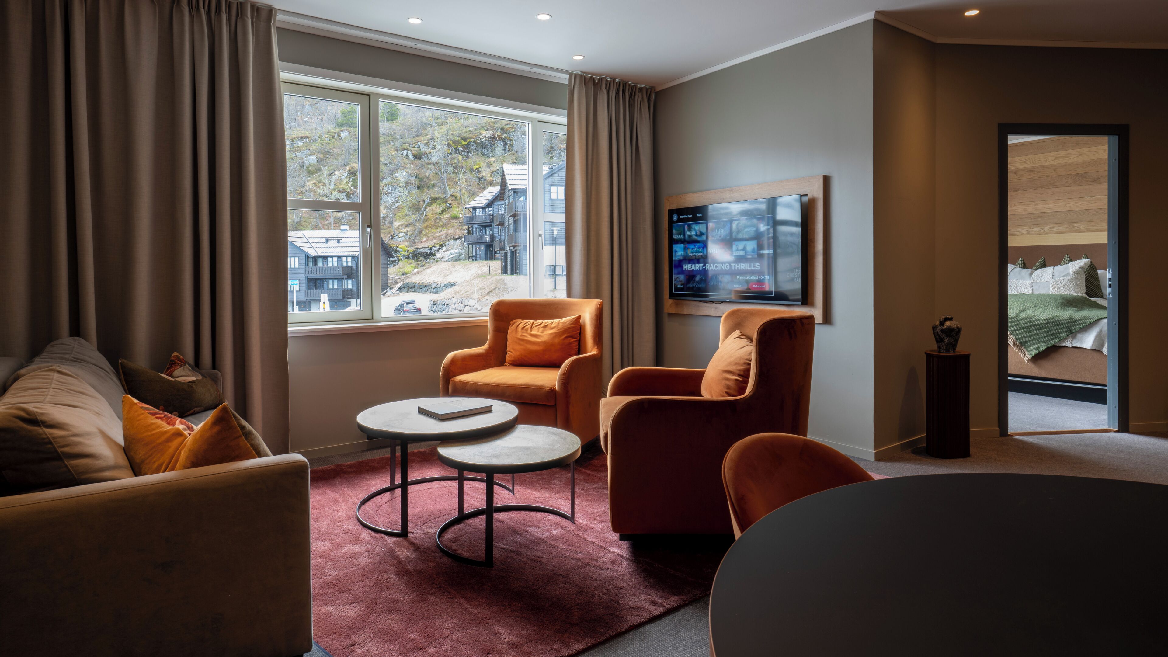A modern living room with a sofa, two armchairs, a coffee table, and a TV.