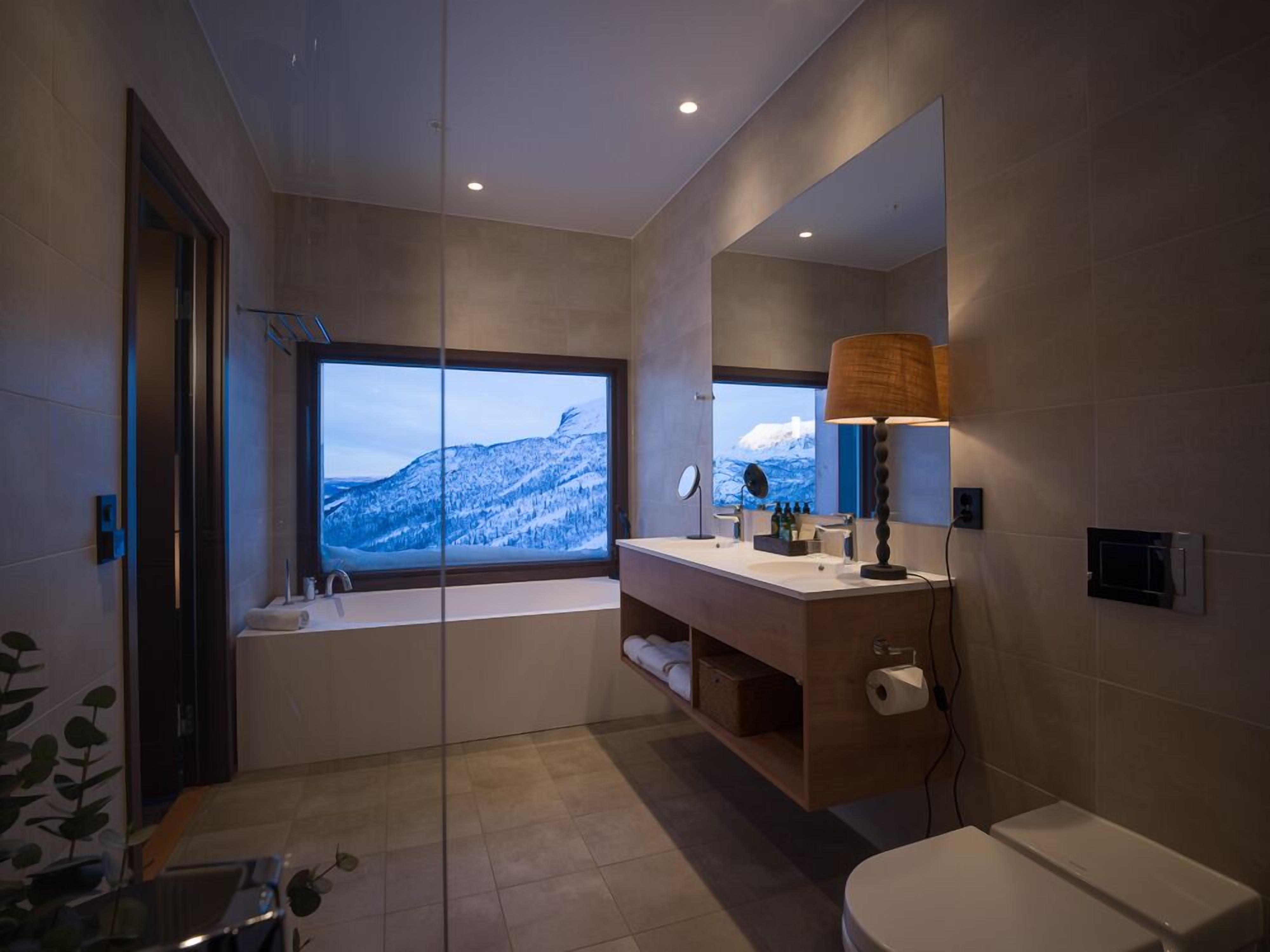 Un baño moderno con un ventanal grande, una bañera, un lavamanos y un inodoro.