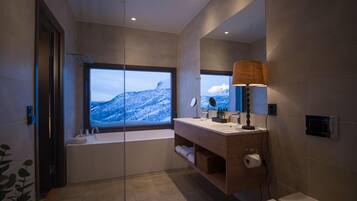 Un baño moderno con un ventanal grande, una bañera, un lavamanos y un inodoro.
