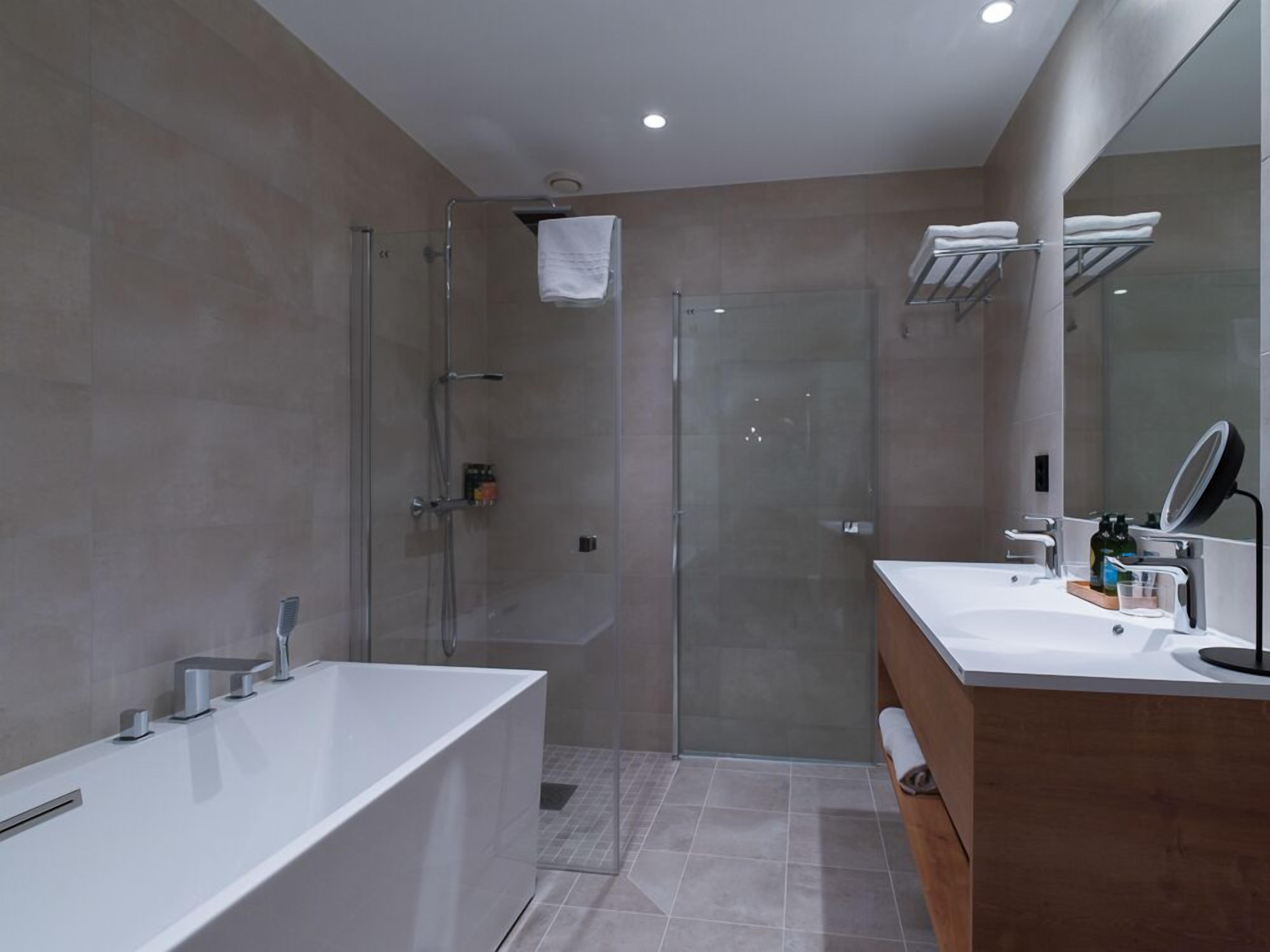 Une salle de bain moderne dotée d’une douche à parois de verre, d’une baignoire sur pieds et d’un meuble-lavabo avec un miroir.