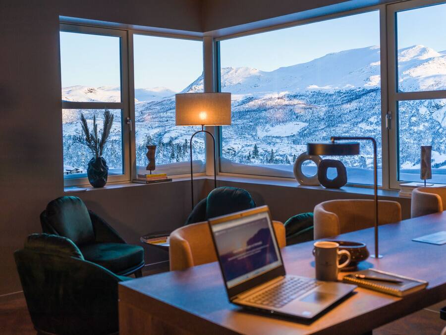 Quarto moderno com uma janela ampla que dá para uma paisagem nevada de montanha.