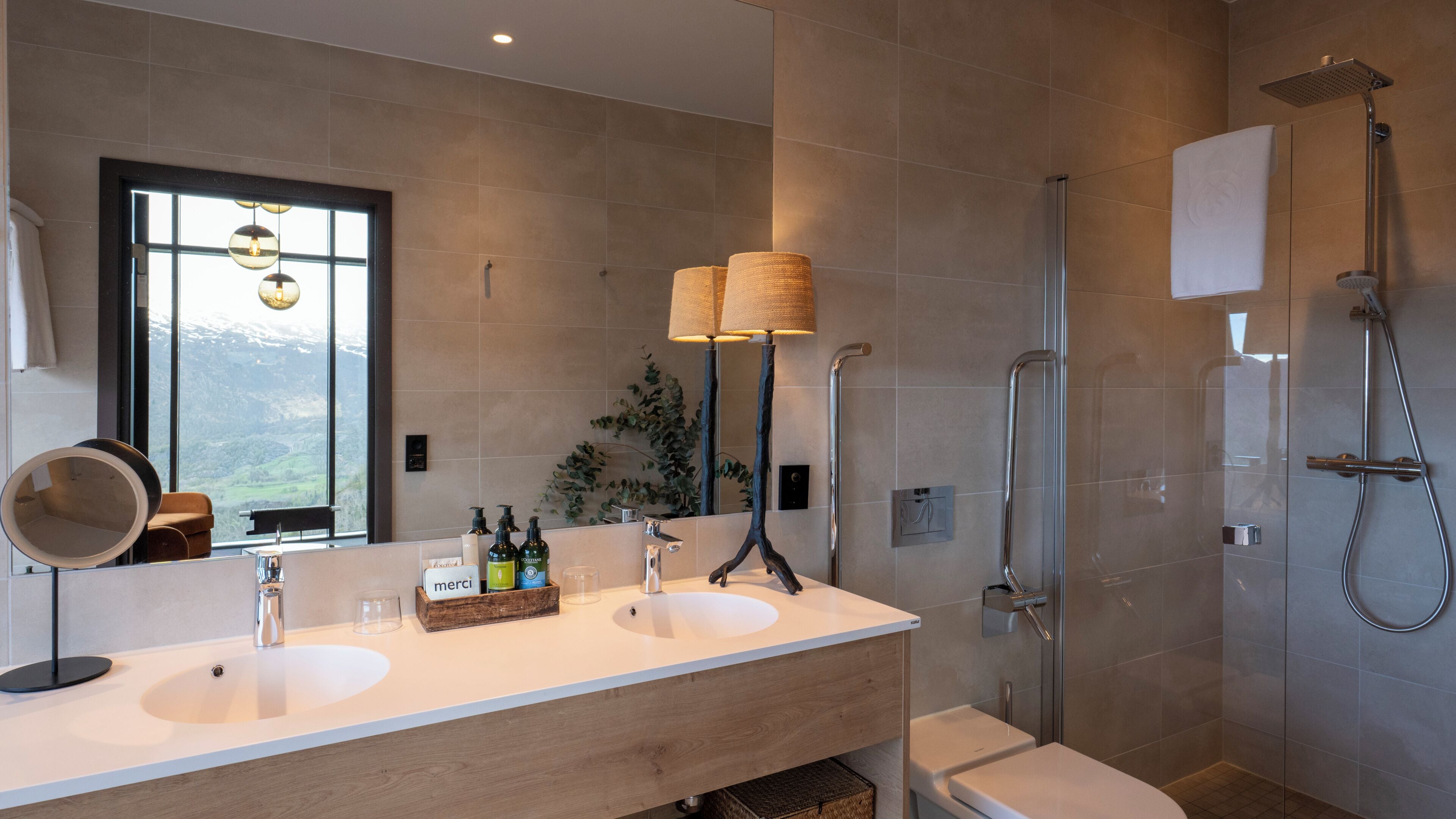 Un baño moderno con dos lavamanos, un espejo grande, una ducha y vistas al exterior.
