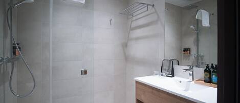 Een moderne badkamer met een douchecabine van glas, een houten wastafelmeubel met spiegel en een handdoekrek.