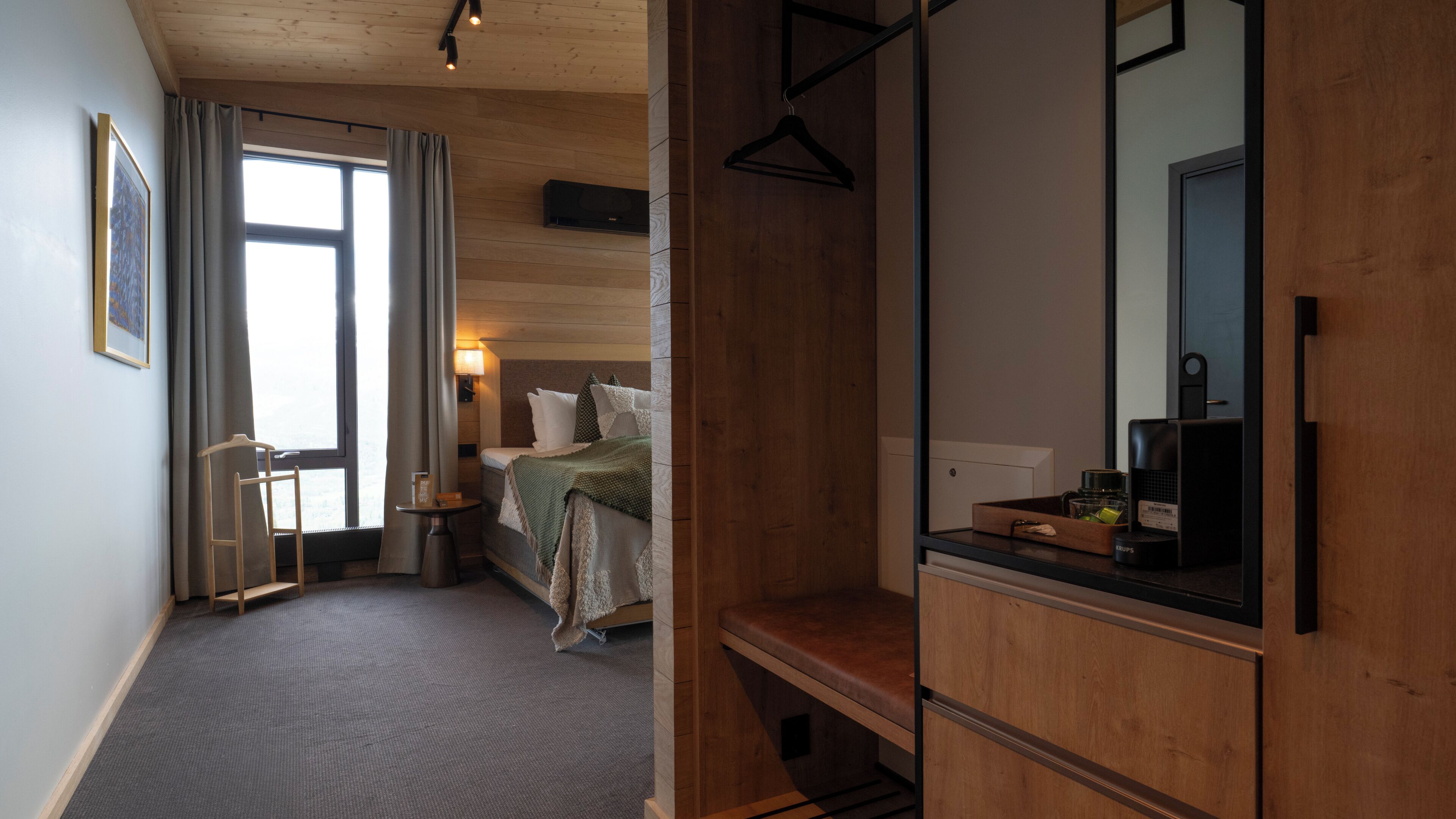 A hotel room with a bed, bedside table, lamp, and a mirror.