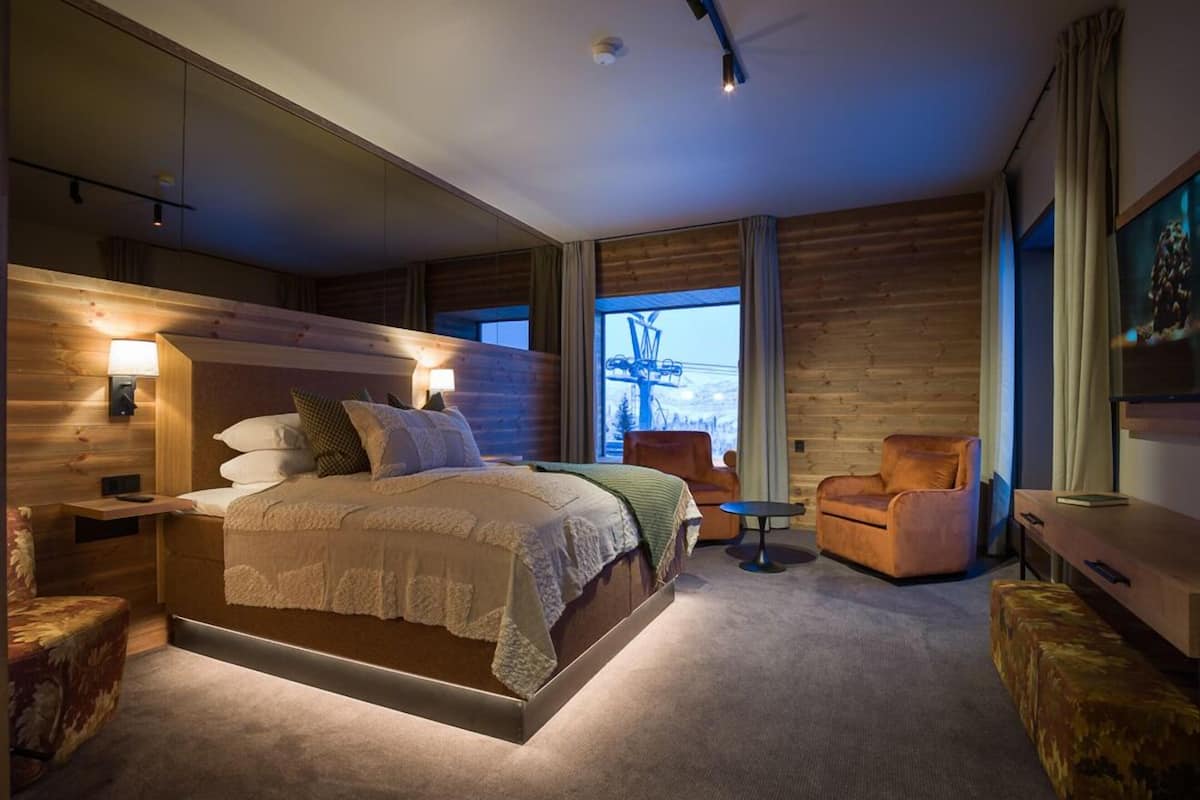 Un dormitorio moderno con una cama grande, una mesita de noche, una silla y una pequeña mesa.