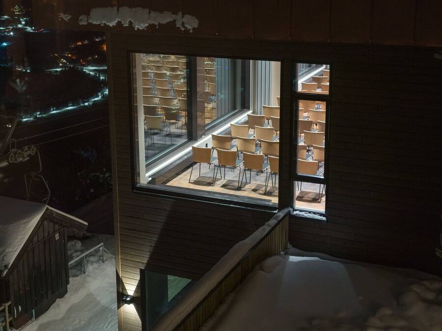 A snow-covered balcony with a view of a restaurant interior.