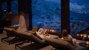 A spa area with reclining chairs, candles, and a large window overlooking a snowy landscape.