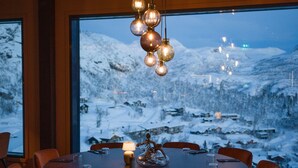 A dining area with a round table, chairs, and a chandelier.