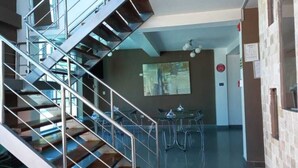 Un interior moderno con una escalera, un área de comedor con sillas y mesas, y una pared con un cuadro.