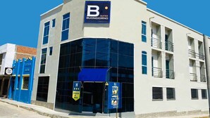 Un hotel moderno con un llamativo letrero en forma de 'B', amplias ventanas y un toldo azul.