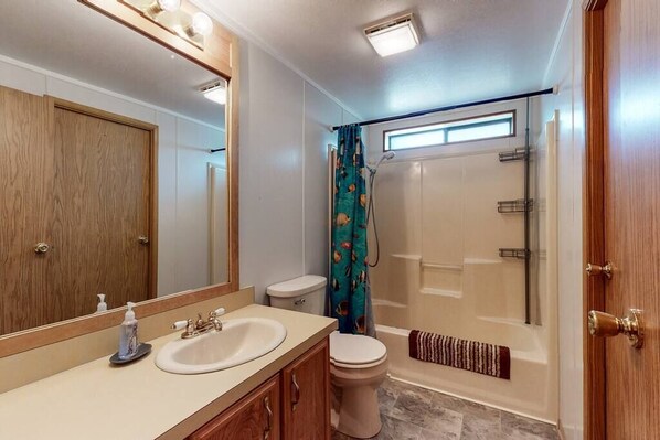 A bathroom with a wooden vanity, a sink, a toilet, and a shower area.