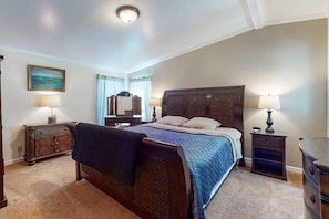 A bedroom with a large bed, two bedside tables with lamps, a dresser, and a painting on the wall.