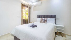 A modern bedroom with a bed, a nightstand, and an air conditioning unit on the wall. - Cosy Hyper center Bd Hassan 2 (Marrakech)