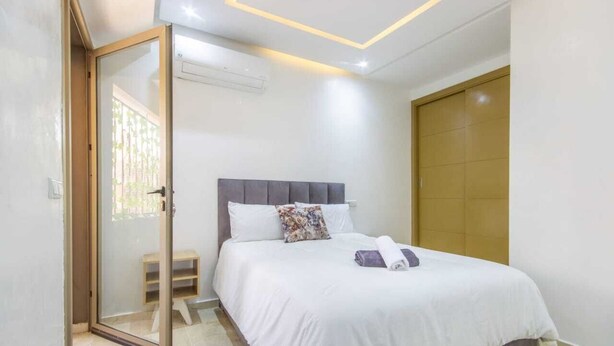 A bedroom with a bed, a sliding glass door, and a closed door. - Cosy Hyper center Bd Hassan 2 (Marrakech)