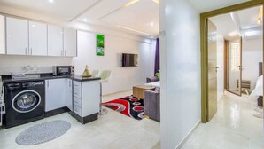 A modern kitchen with built-in appliances, a washing machine, and a dining area with a small table and chairs. - Cosy Hyper center Bd Hassan 2 (Marrakech)