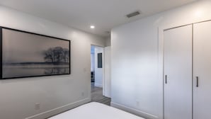 A bedroom with a large bed, a wardrobe, and a framed picture on the wall. - Beach Oasis with Private Pool (Fort Lauderdale)