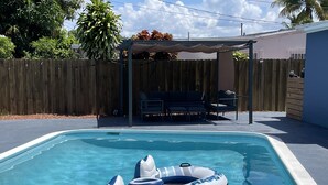 A rectangular swimming pool with clear blue water, surrounded by a wooden fence. - Beach Oasis with Private Pool (Fort Lauderdale)