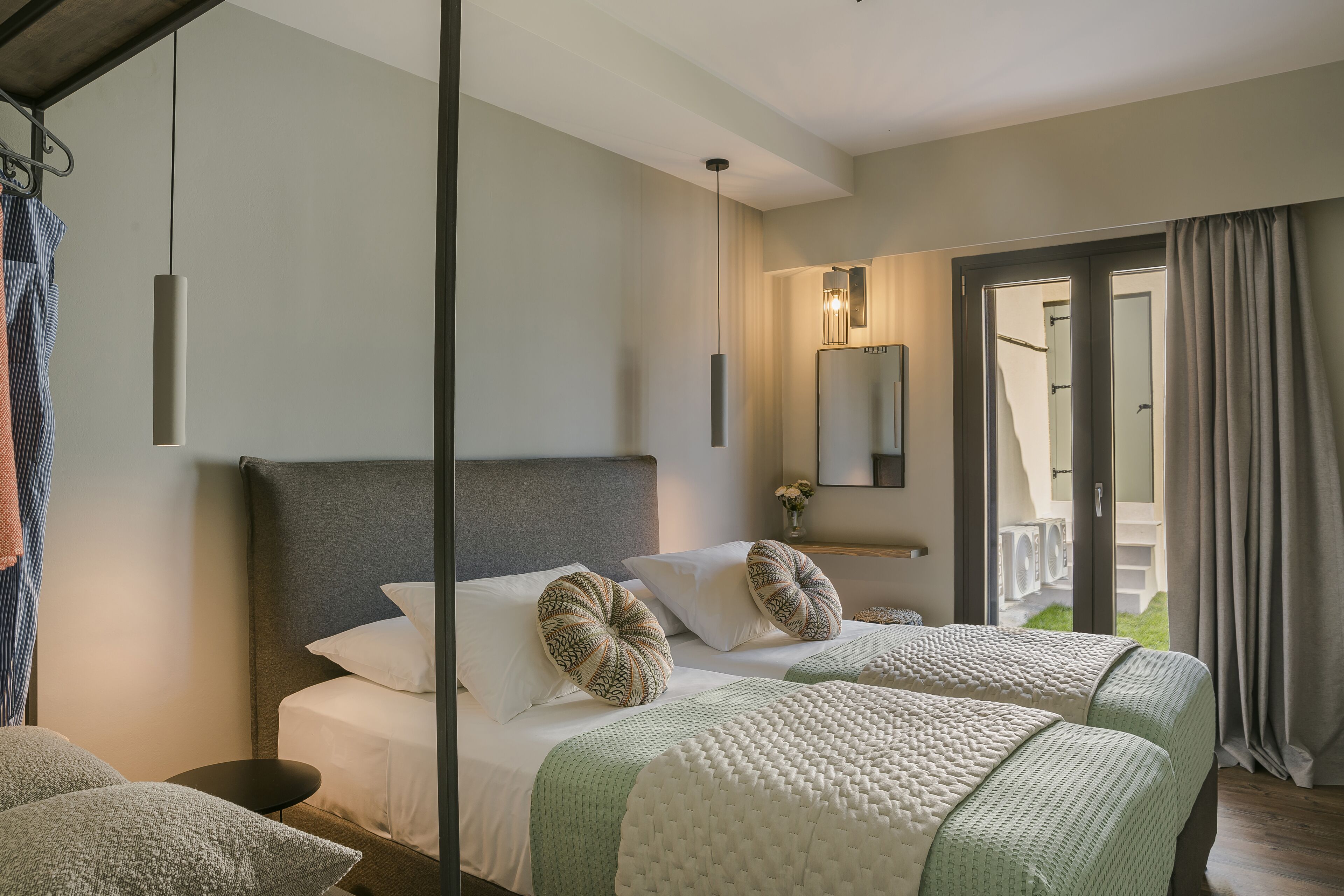 A hotel room with a large bed, two pillows, a bedside table, and a mirror.