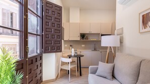 A compact living space with a kitchenette, a dining area, and a sofa. - Líbere Málaga La Merced (Málaga)