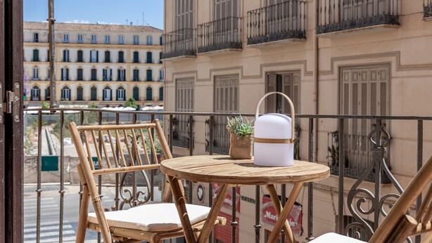A balcony with a wooden table, two chairs, and a potted plant. - Líbere Málaga La Merced (Málaga)