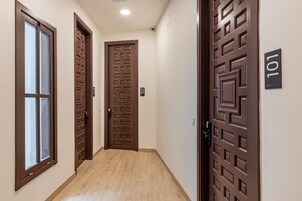 A hallway with three wooden doors, each with a different design, and a number '101' on the wall.