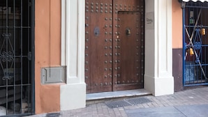 A building with a large wooden double door, a small window with a circular design, and a number '73' sign above the door. - Líbere Málaga La Merced (Málaga)