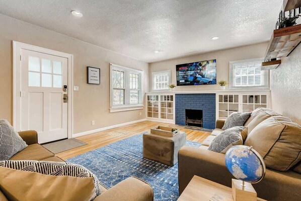 A living room with a fireplace, a TV mounted above it, and a sofa set.
