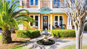 Una casa de dos pisos con un porche delantero, una fuente decorativa y un jardín bien cuidado.