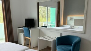Habitación de hotel con dos camas, un escritorio con computadora, una silla y un espejo grande.